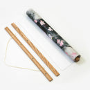 Wooden sticks with floral-patterned cylindrical container on a white background